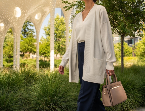 Women in cream cardigan carrying a handbag, walking through Park Row luxury condominium in Downtown Bellevue, Washington.